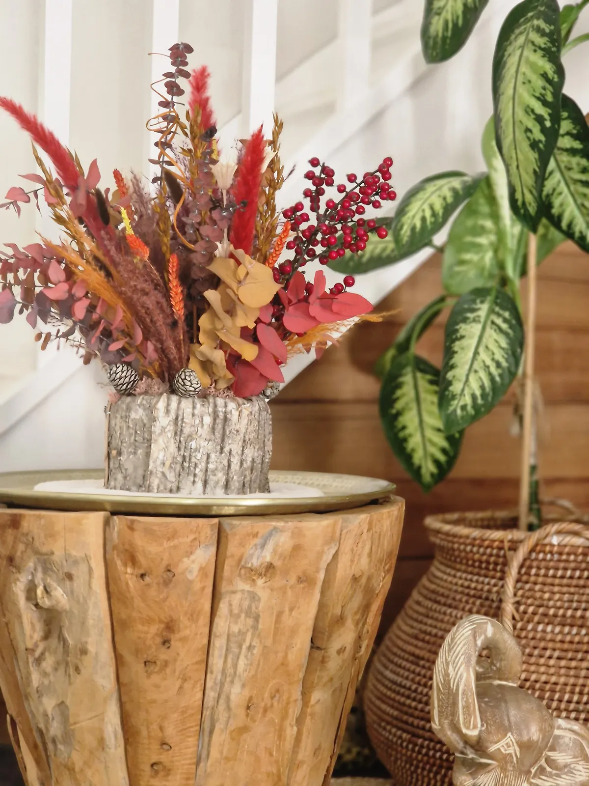 Composition de fleurs séchées aux tons terracotta sur un rondin de bois