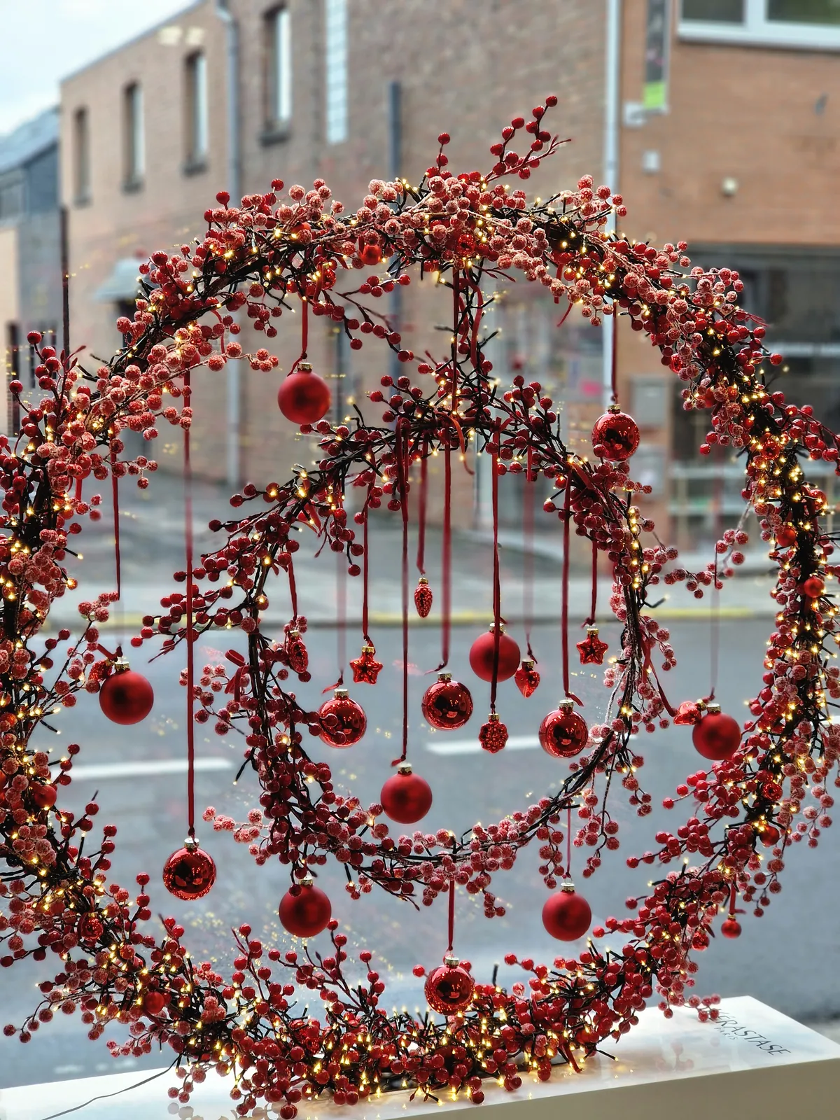 Couronne de 1m de diamètre garnie de baies rouges, illuminée (sur secteur), de boules et d'une couronne au centre