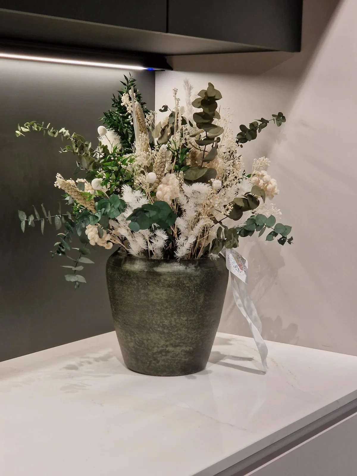 Montage en fleurs séchées et eucalyptus stabilisé, pot en grès vert — location mensuelle 30 € HTVA/mois