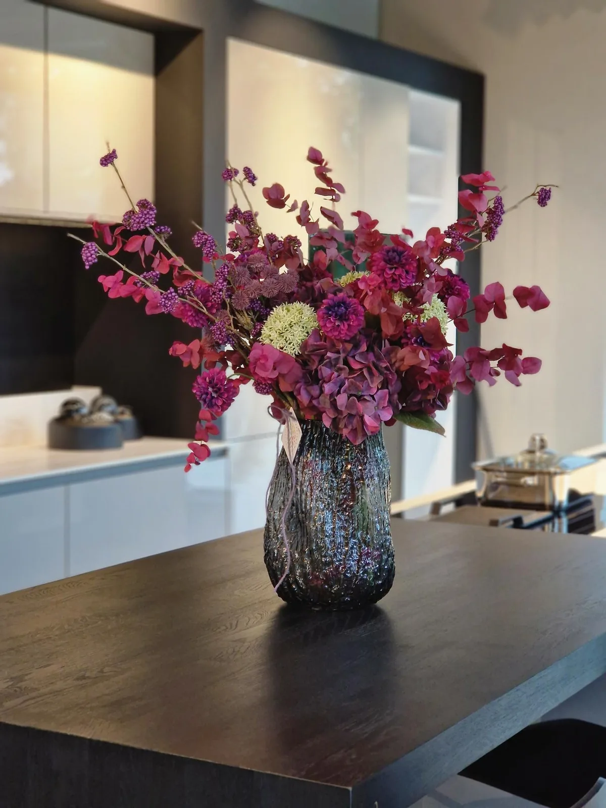 Montage en tons prune et fuchsia, hortensias et dahlias, vase en verre texturé — location mensuelle 30 € HTVA/mois